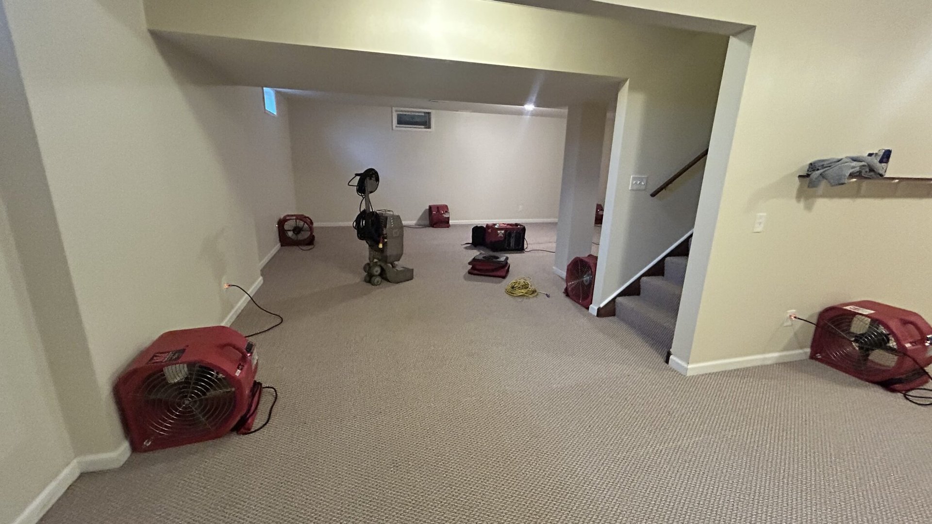 Air movers spaced across an indoor room during drying