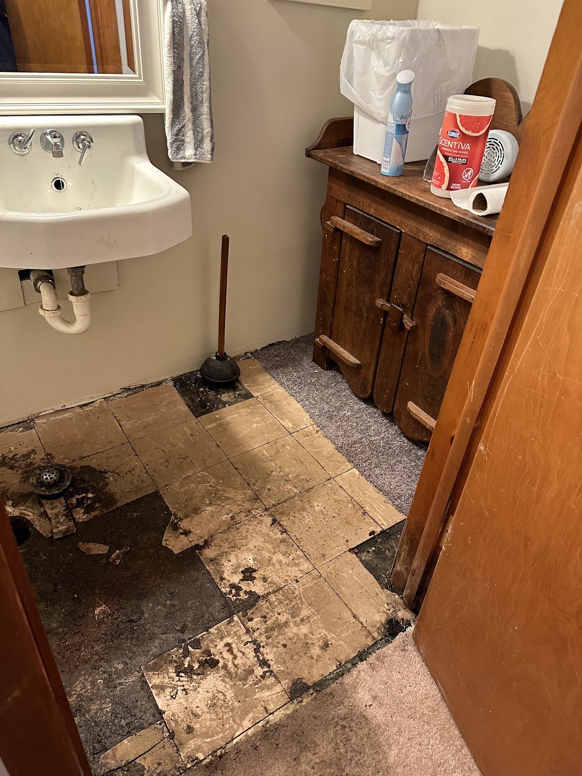 Damaged bathroom flooring and exposed material around a drain opening