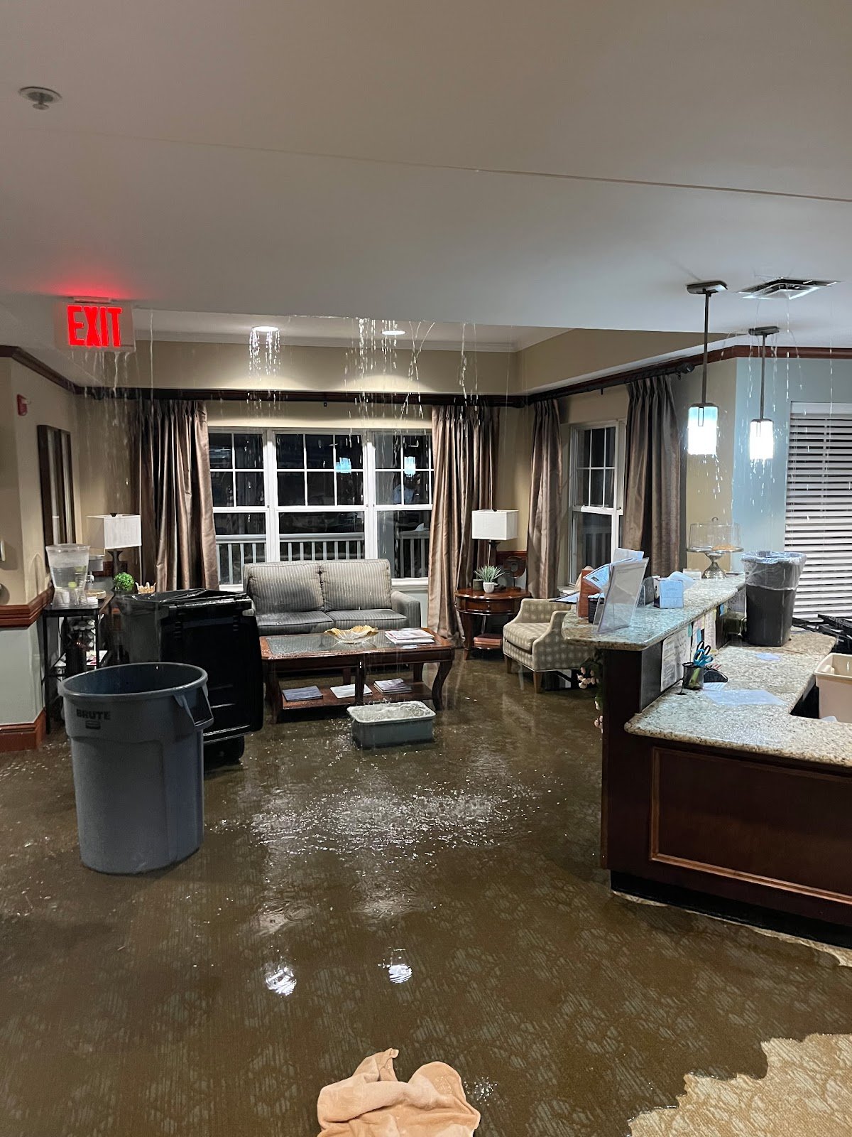 Standing water across a commercial room floor with cleanup containers
